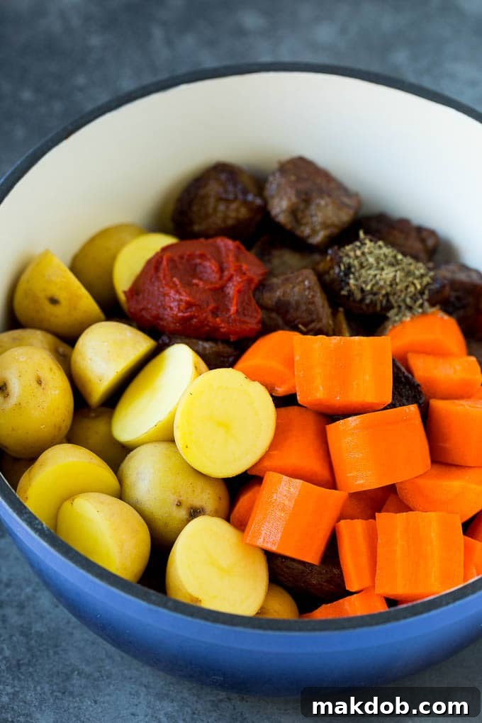 Ingredients for Irish Stew in a Pot Diced beef, chunky potatoes, sliced carrots, and tomato paste ready to be mixed in a large pot for Irish stew.
