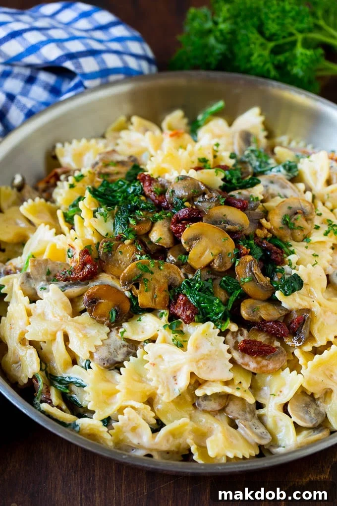 Farfalle pasta with spinach and mushrooms in a creamy sauce, ready to be served.