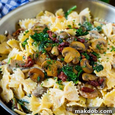 Farfalle pasta with spinach and mushrooms in a creamy sauce.