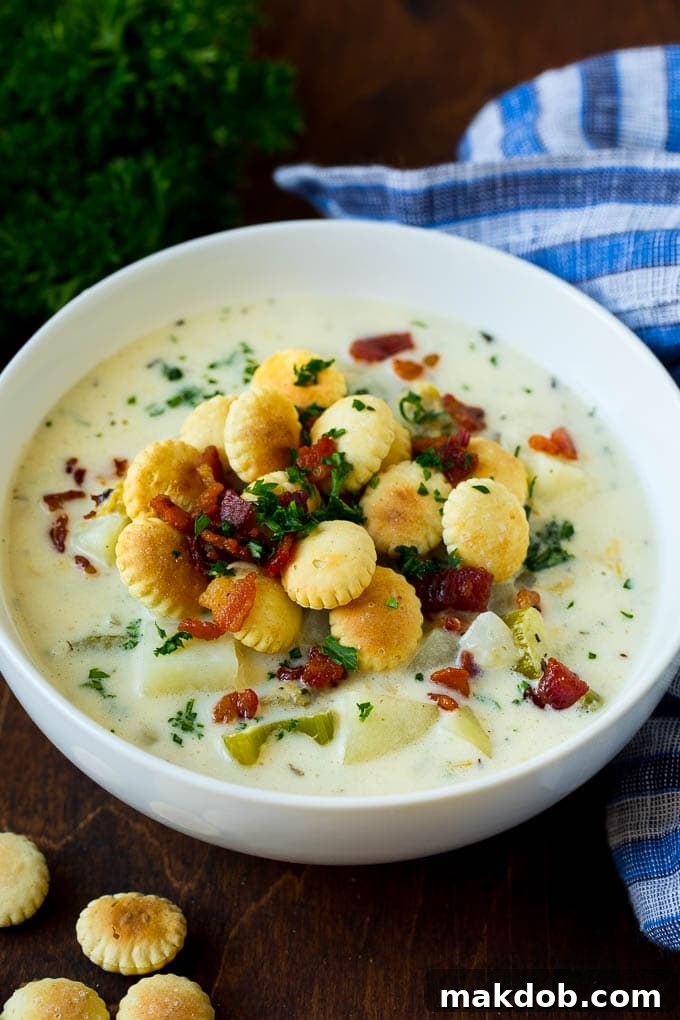 New England Clam Chowder Recipe | White Clam Chowder #chowder #soup #seafood #clams #bacon #dinner #dinneratthezoo A bowl of New England clam chowder topped with bacon and crackers.