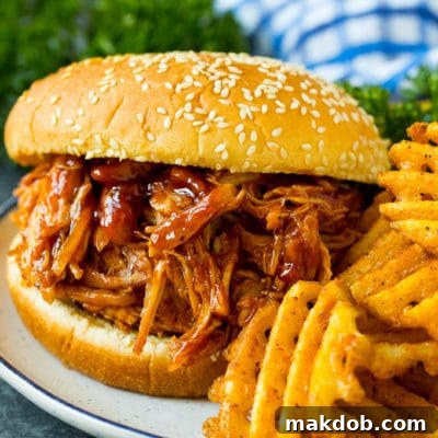 Effortless Slow Cooker BBQ Chicken 2 Crockpot BBQ chicken on a bun served with french fries.