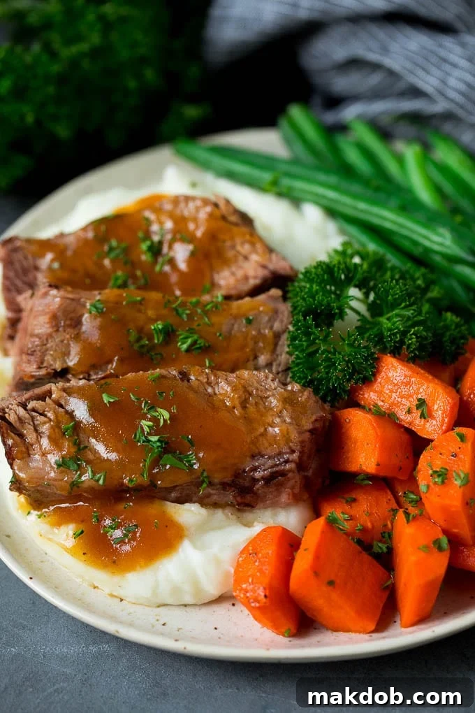 Slow cooker brisket served over mashed potatoes with vegetables on the side.
