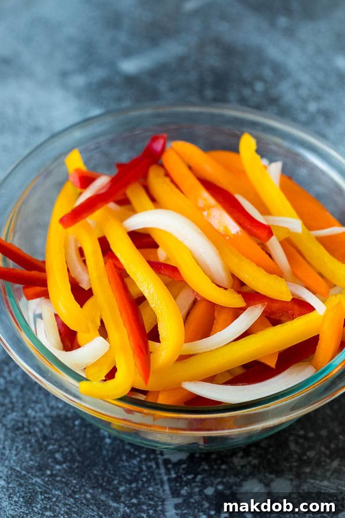 Chicken Fajita Marinade Recipe | Chicken Fajitas #chicken #fajitas #marinade #dinner #dinneratthezoo Sliced bell peppers and onions in a bowl, ready for fajita preparation.
