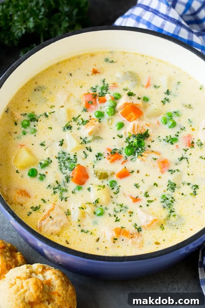 Chicken Pot Pie Soup with Cheddar Biscuits on the Side Close-up of a bowl of creamy chicken pot pie soup, served with freshly baked cheddar biscuits on the side, ready for dipping.