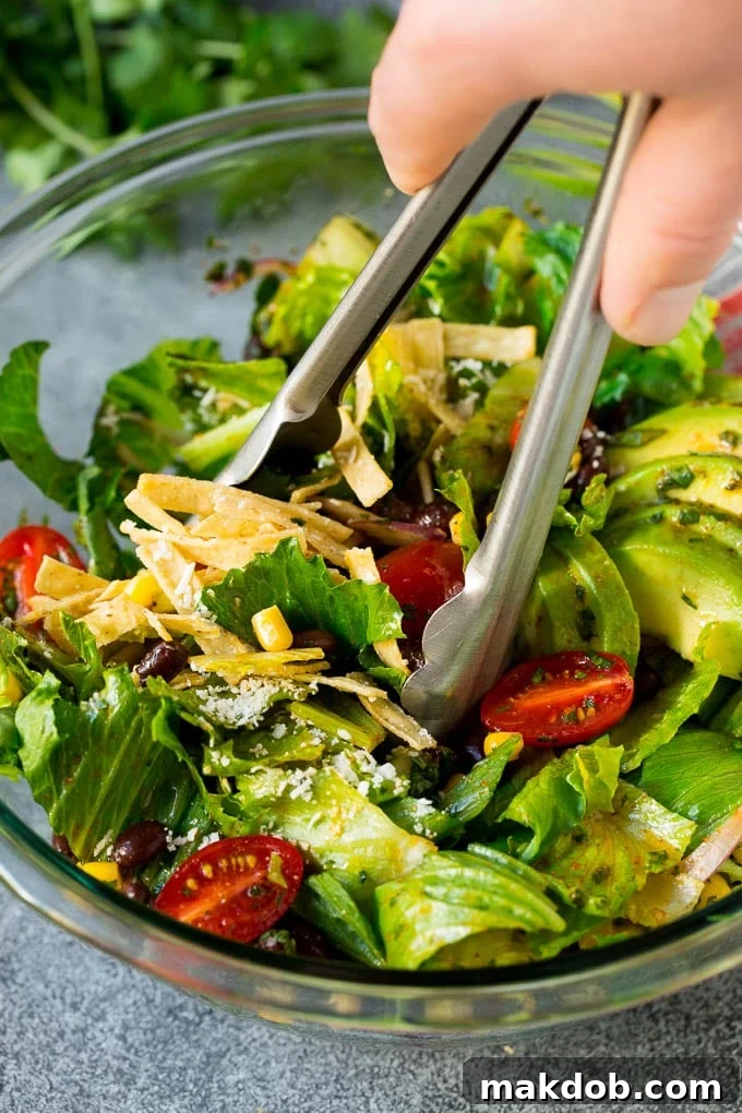 Tongs serving up a portion of Mexican salad.
