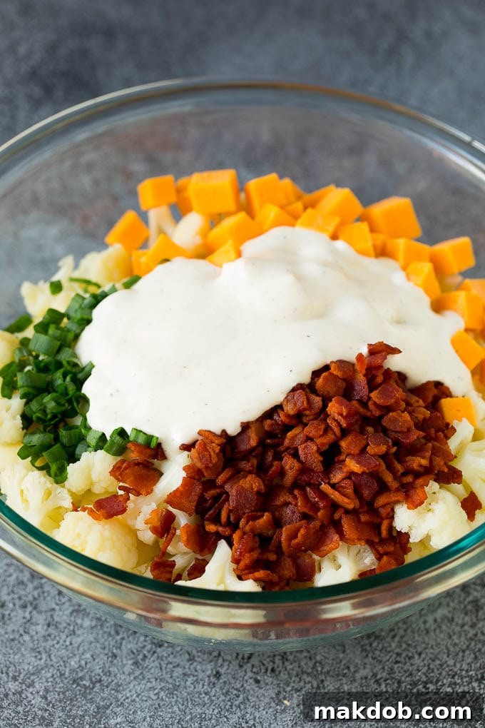 Cauliflower, bacon, cheese and green onions topped with a creamy dressing, ready to be tossed.