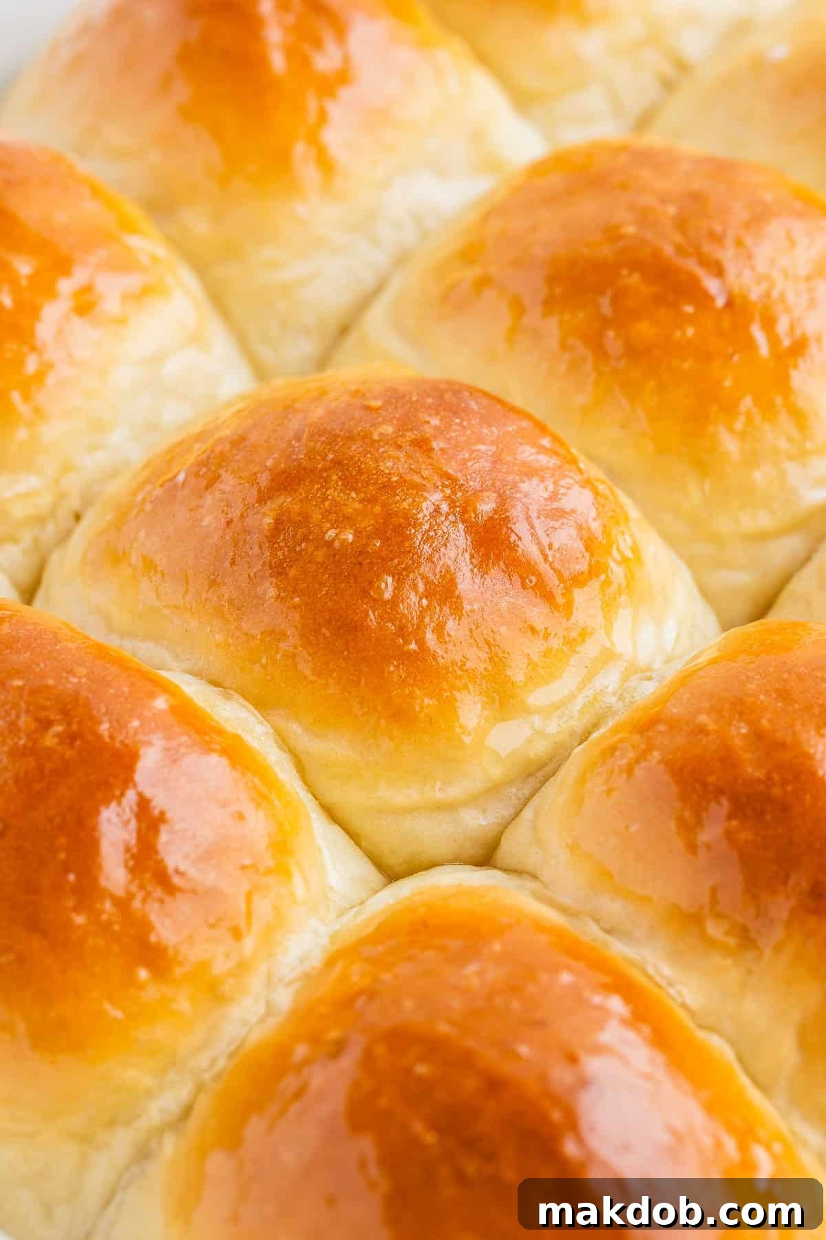A tantalizing close-up view of golden-brown homemade dinner rolls, showing their soft texture and fluffy interior, inviting a warm bite.