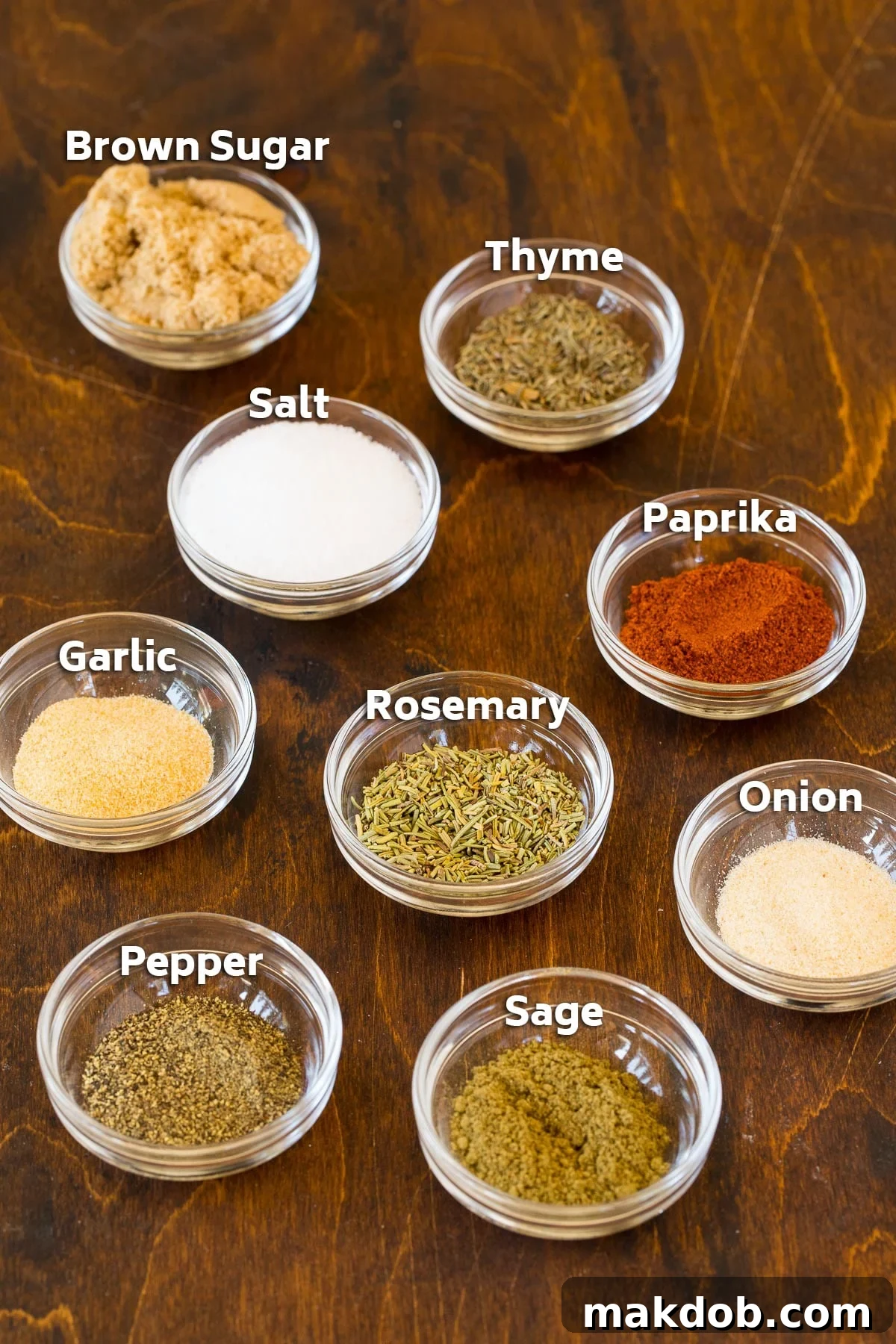 Ultimate Turkey Rub 3 Assorted bowls showcasing key turkey rub ingredients: kosher salt, brown sugar, paprika, black pepper, dried thyme, dried rosemary, dried sage, garlic powder, and onion powder.