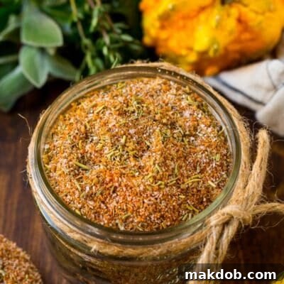 A jar of homemade turkey rub, surrounded by autumnal squash and fresh herbs, ready to impart rich flavor to any poultry or meat dish.