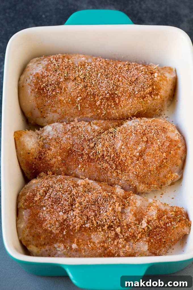 Chicken coated in seasonings in a baking dish.