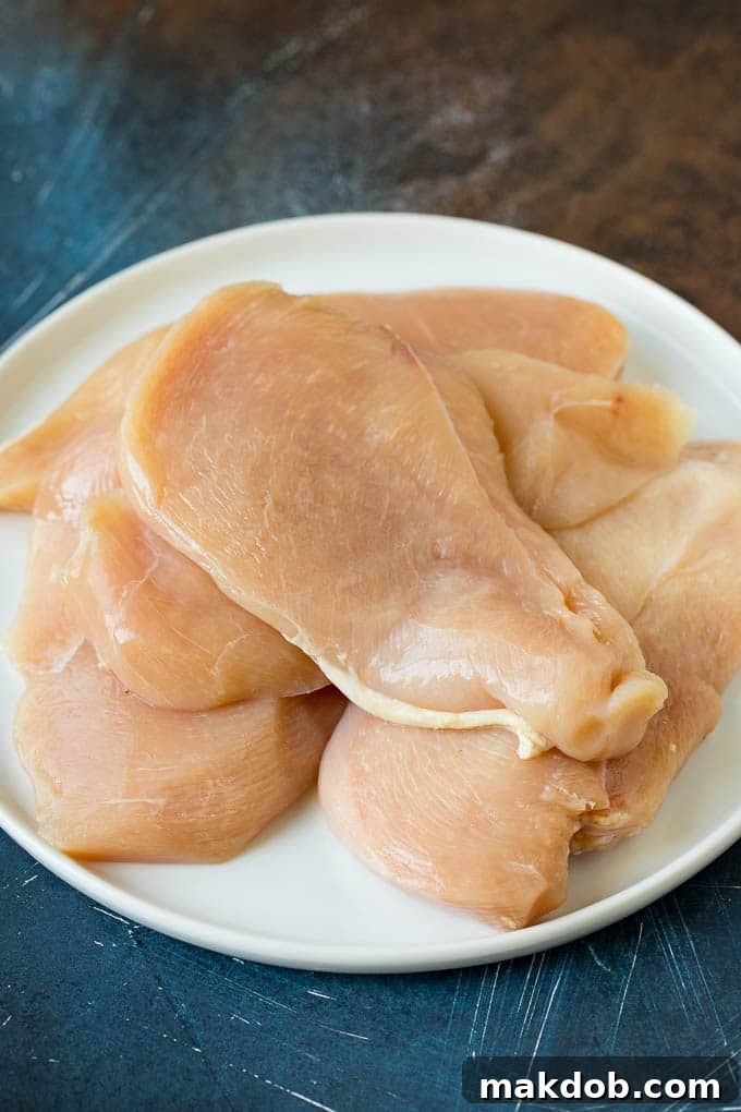Thinly sliced chicken breasts on a white plate, ready for battering.
