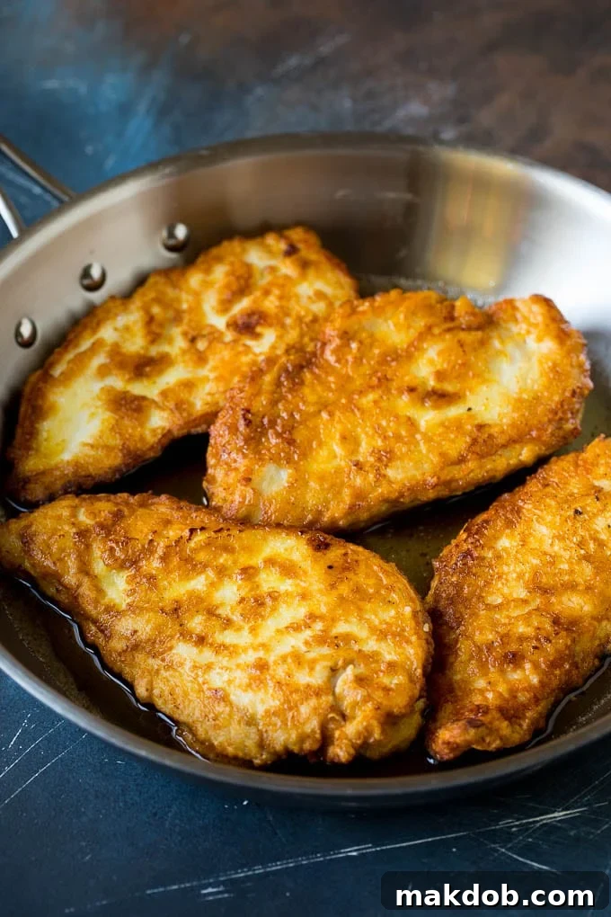 Battered and pan-fried chicken cutlets in a skillet, ready for the sauce.
