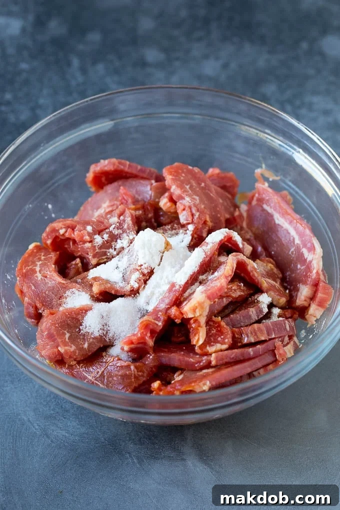 Marinating Flank Steak for Tender Beef Chow Mein Sliced flank steak and cornstarch in a bowl, ready for marinating.