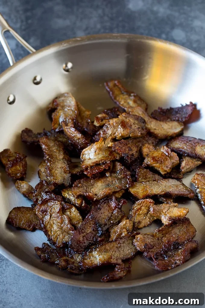 Perfectly Seared Steak for Beef Chow Mein Seared steak slices sizzling in a pan, ready for vegetables.