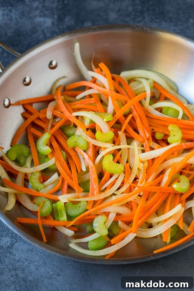 Fresh Vegetables Sautéing for Beef Chow Mein Cooked carrots, onions, and celery in a skillet, awaiting other ingredients.