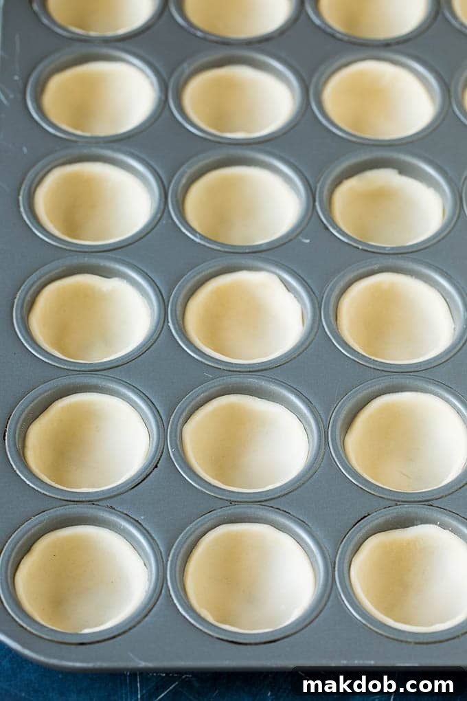 Mini Quiche Recipe #eggs #breakfast #brunch #appetizer #dinneratthezoo Neatly pressed pie crust rounds lining a mini muffin tin, ready for filling.