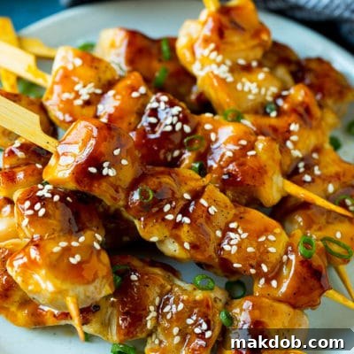 Japanese Grilled Chicken Skewers 2 A plate of grilled chicken yakitori topped with sesame seeds and green onions.