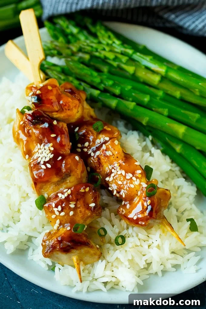Yakitori with Rice and Asparagus | Complete Meal Serving of grilled chicken yakitori skewers arranged neatly over a bed of fluffy steamed rice, garnished with vibrant green asparagus spears.