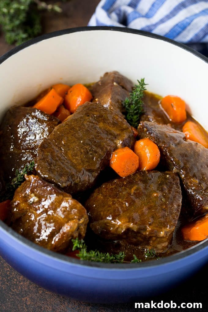Best Braised Short Ribs Recipe - Easy & Flavorful Beef Dinner Braised short ribs with carrots in a blue pot, garnished with fresh thyme. A perfect comfort food recipe.