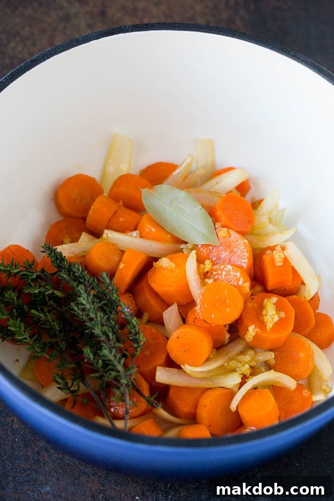 Ingredients for Braised Short Ribs Sauce Carrots, onions, and fresh herbs cooking in a pot, forming the base for the braised short ribs sauce.