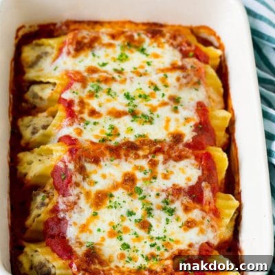 A dish of baked manicotti pasta topped with melted cheese and parsley.