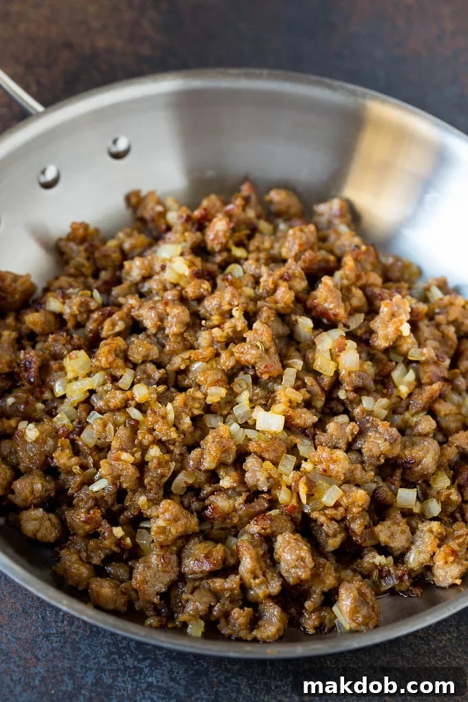 Close-up of browned Italian sausage and onions cooking in a skillet.