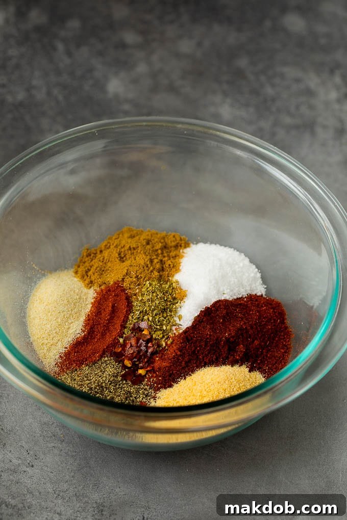 Homemade taco seasoning with a savory mix of spices, this blend can be used in all different types of Mexican food. Herbs and spices in a mixing bowl, being stirred together to create a flavorful seasoning blend.