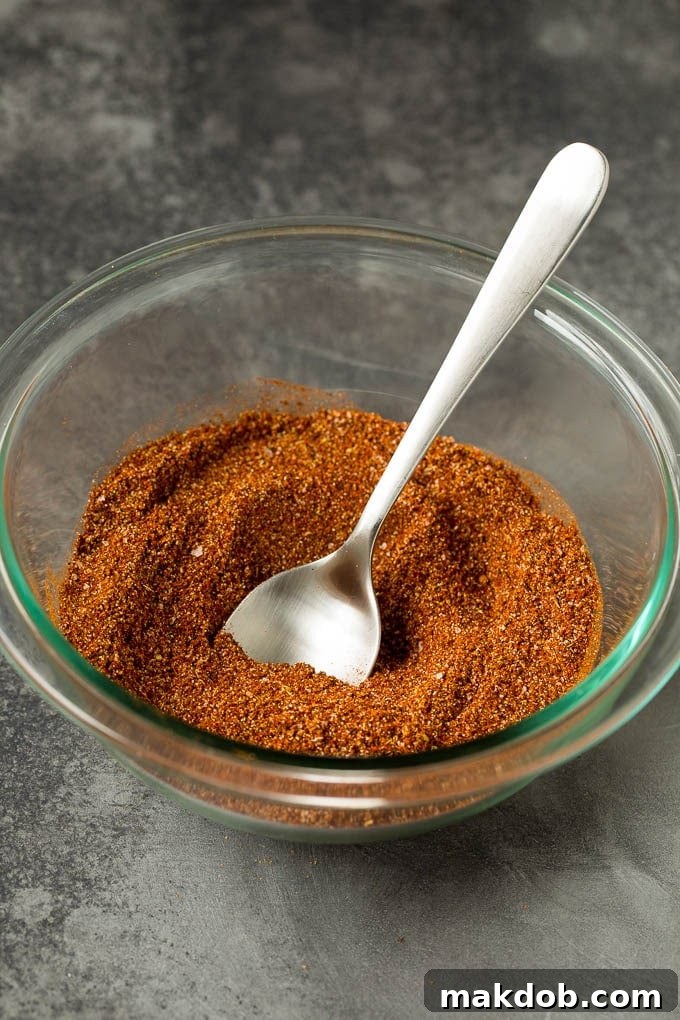 Homemade taco seasoning with a savory mix of spices, this blend can be used in all different types of Mexican food. Spices stirred together to make a Mexican seasoning, showcasing the rich colors and textures.