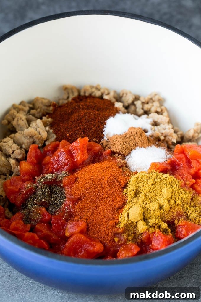 Close-up of ground turkey, tomato sauce, and a blend of spices simmering in a soup pot, capturing the rich texture of the chili.