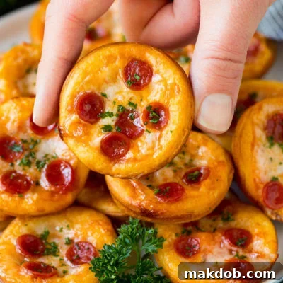 A platter of mini pizzas with a hand reaching for one.