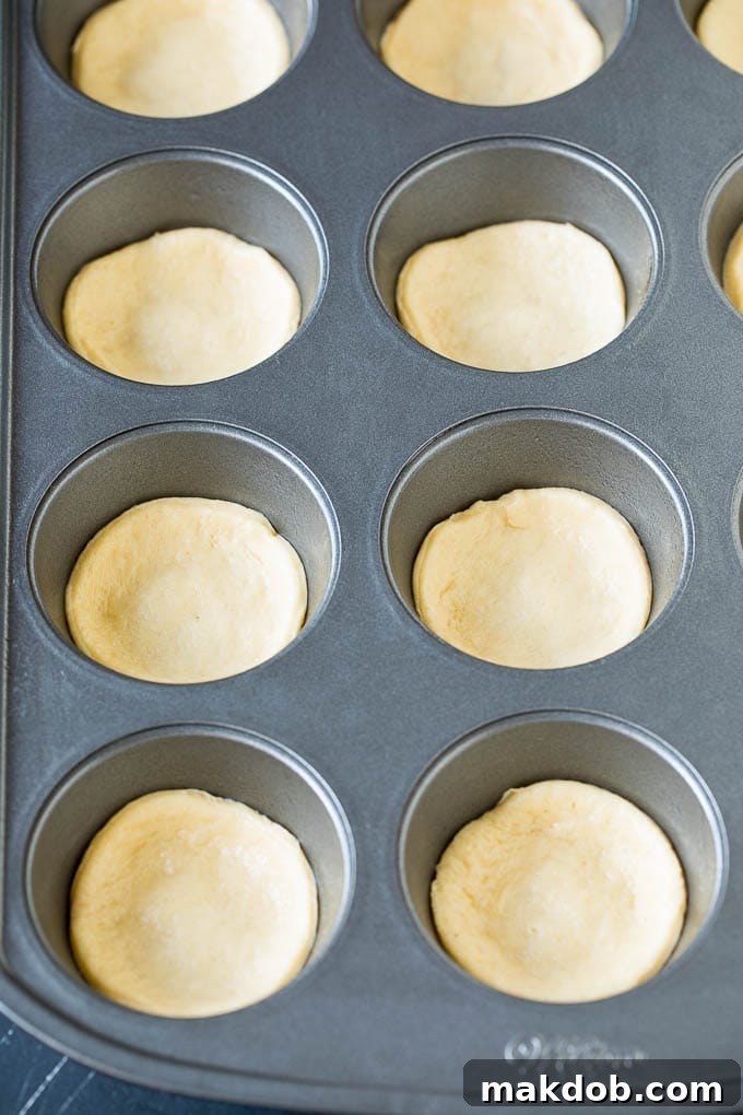 Mini pizzas topped with pepperoni are a fun and easy appetizer option. #pizza #dinneratthezoo #appetizer Dough circles pressed into muffin cups.