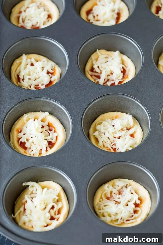 Mini pizzas topped with pepperoni are a fun and easy appetizer option. #pizza #dinneratthezoo #appetizer Circles of dough topped with pizza sauce and shredded cheese.