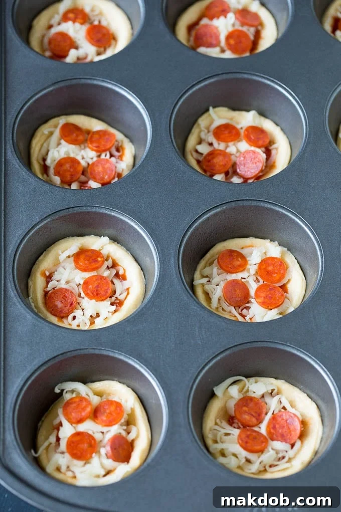 Mini pizzas topped with pepperoni are a fun and easy appetizer option. #pizza #dinneratthezoo #appetizer Dough topped with sauce, cheese and mini pepperoni.