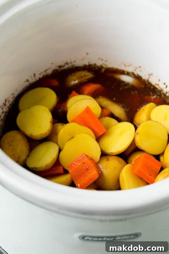 Potatoes, carrots and seasonings in a crockpot.