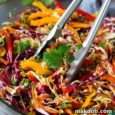 Crisp Asian Sesame Slaw 2 Tongs serving up a portion of Asian slaw.