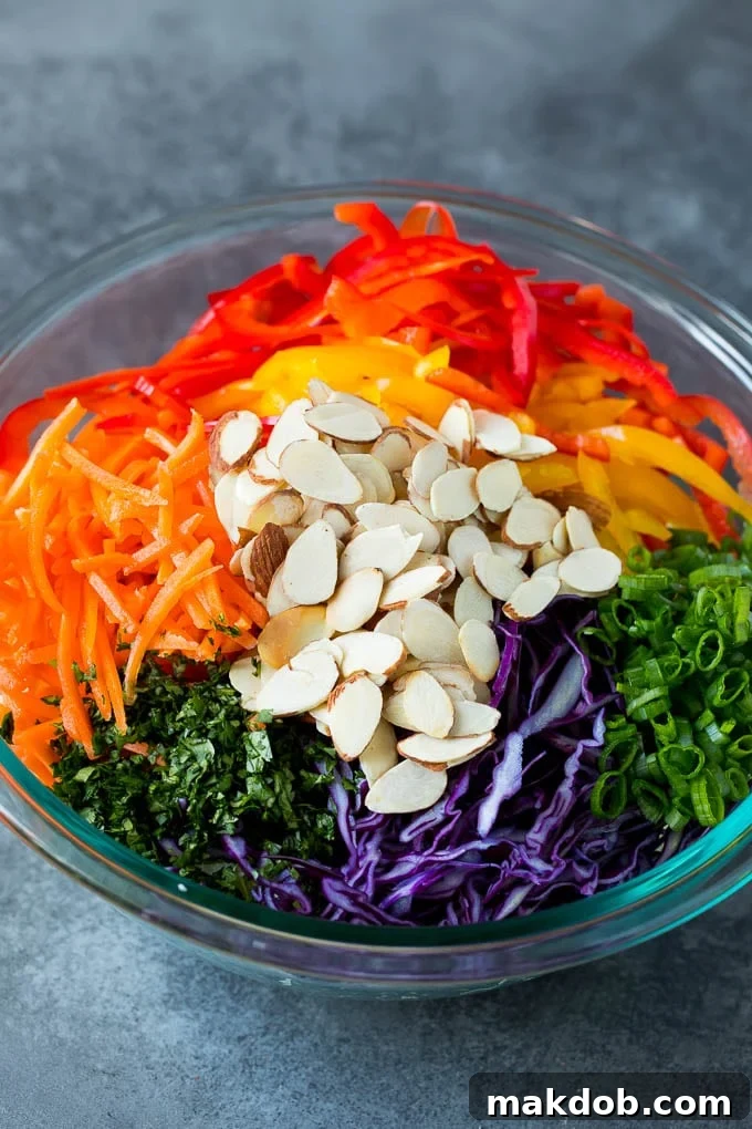 Asian Slaw Shredded cabbage, vegetables and almonds in a bowl.