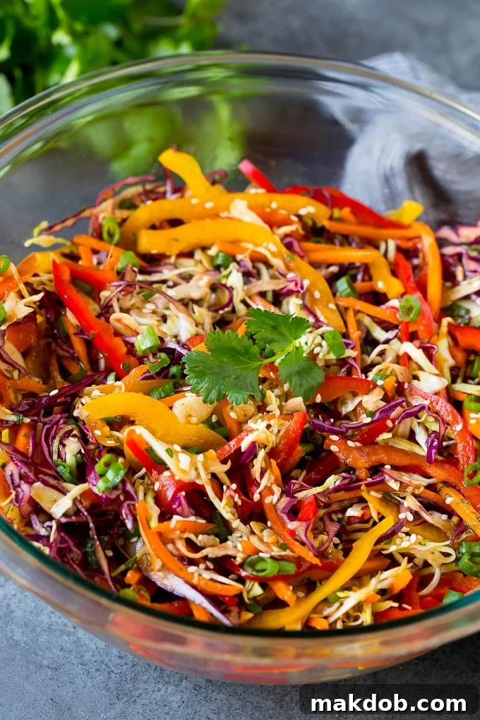 A beautifully arranged bowl of Asian slaw, garnished with fresh sesame seeds and herbs.