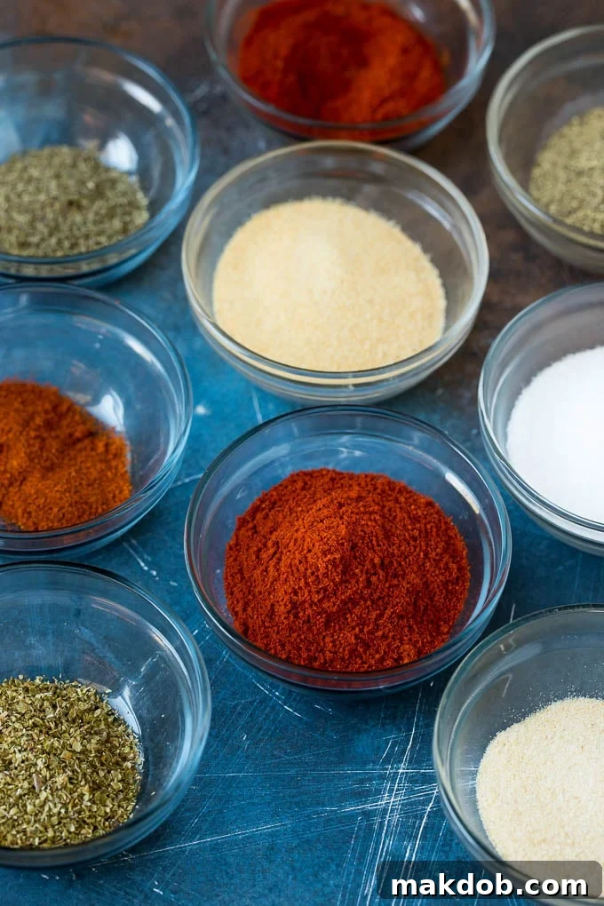 Homemade Cajun seasoning made with a unique blend of herbs and spices. #cajun #dinneratthezoo Several bowls showcasing individual spices like paprika, garlic powder, and onion powder, ready for mixing to create Cajun seasoning.