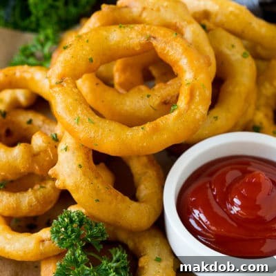 Fried onion rings on a plate with a side of ketchup.