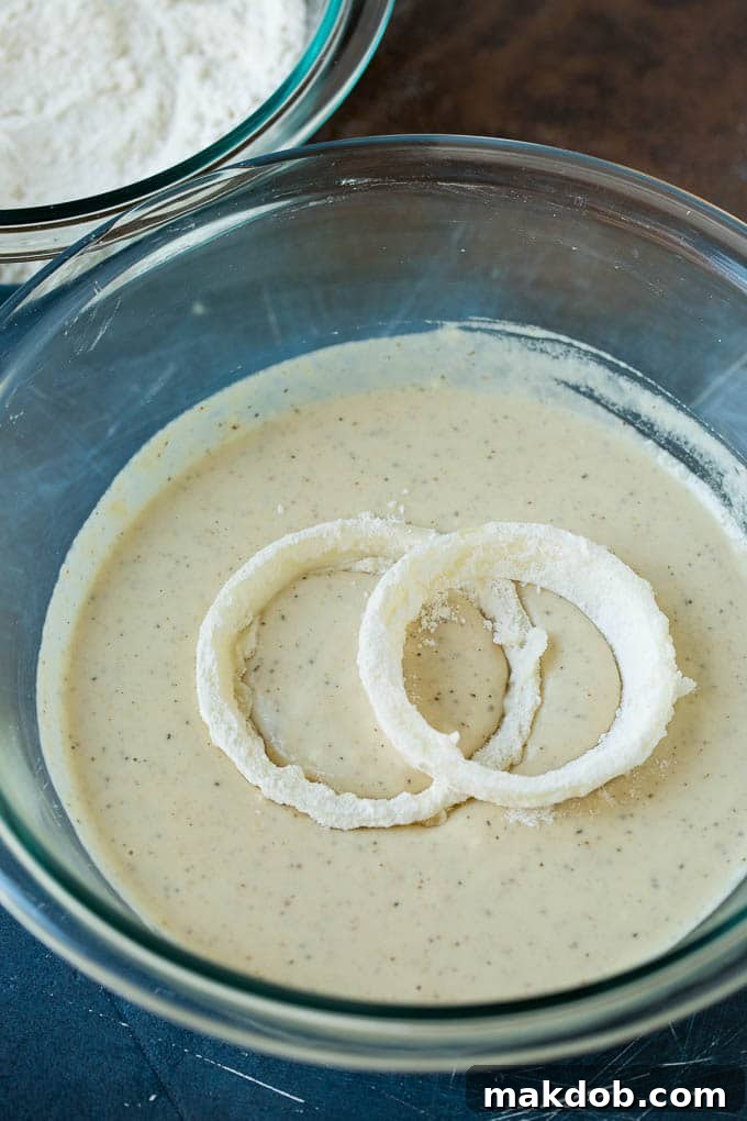 Floured onions in a bowl of beer batter.