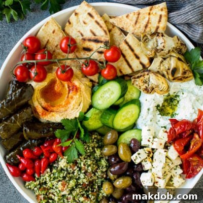 A mezze platter filled with dips, pita bread, vegetables, olives and cheese.