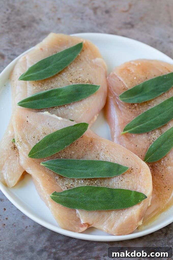 Thinly sliced raw chicken breasts with fresh sage leaves placed on top, ready for seasoning and wrapping.
