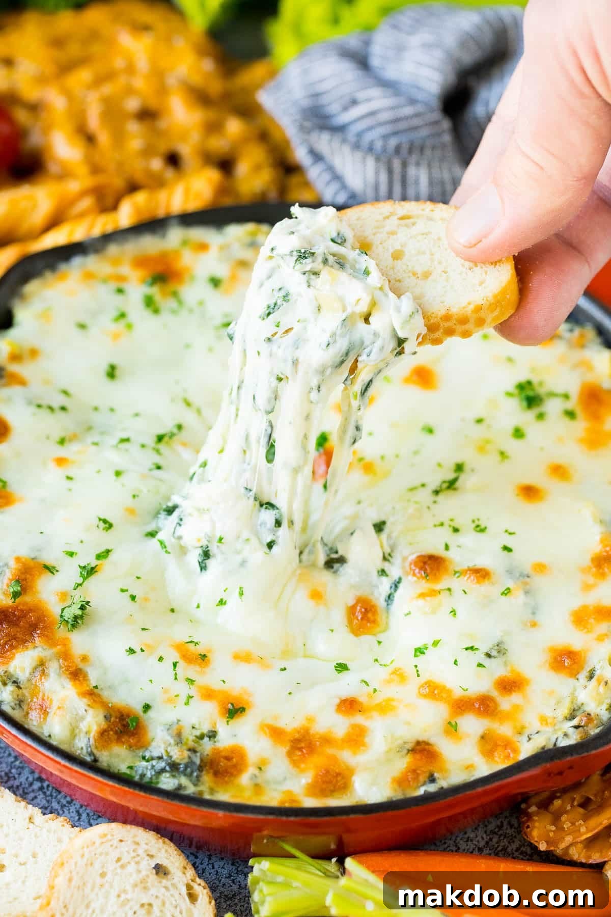 A slice of bread scooping up a serving of spinach artichoke dip.