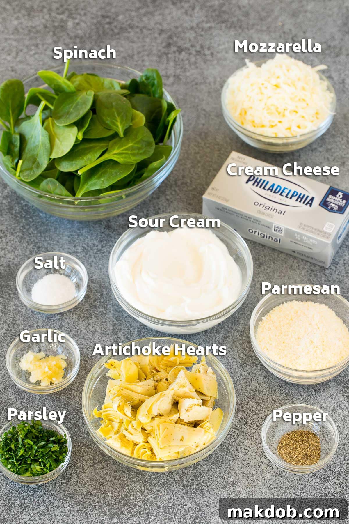 Bowls of ingredients including sour cream, cheese, spinach and artichokes.