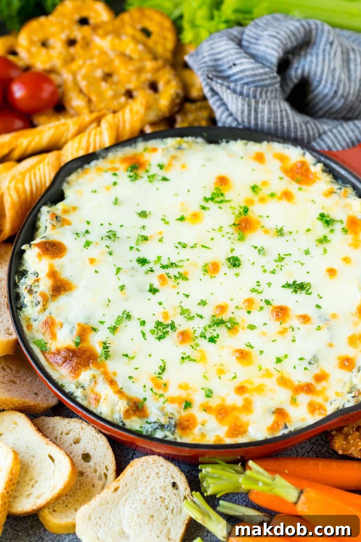 A pan of spinach artichoke dip topped with parsley.