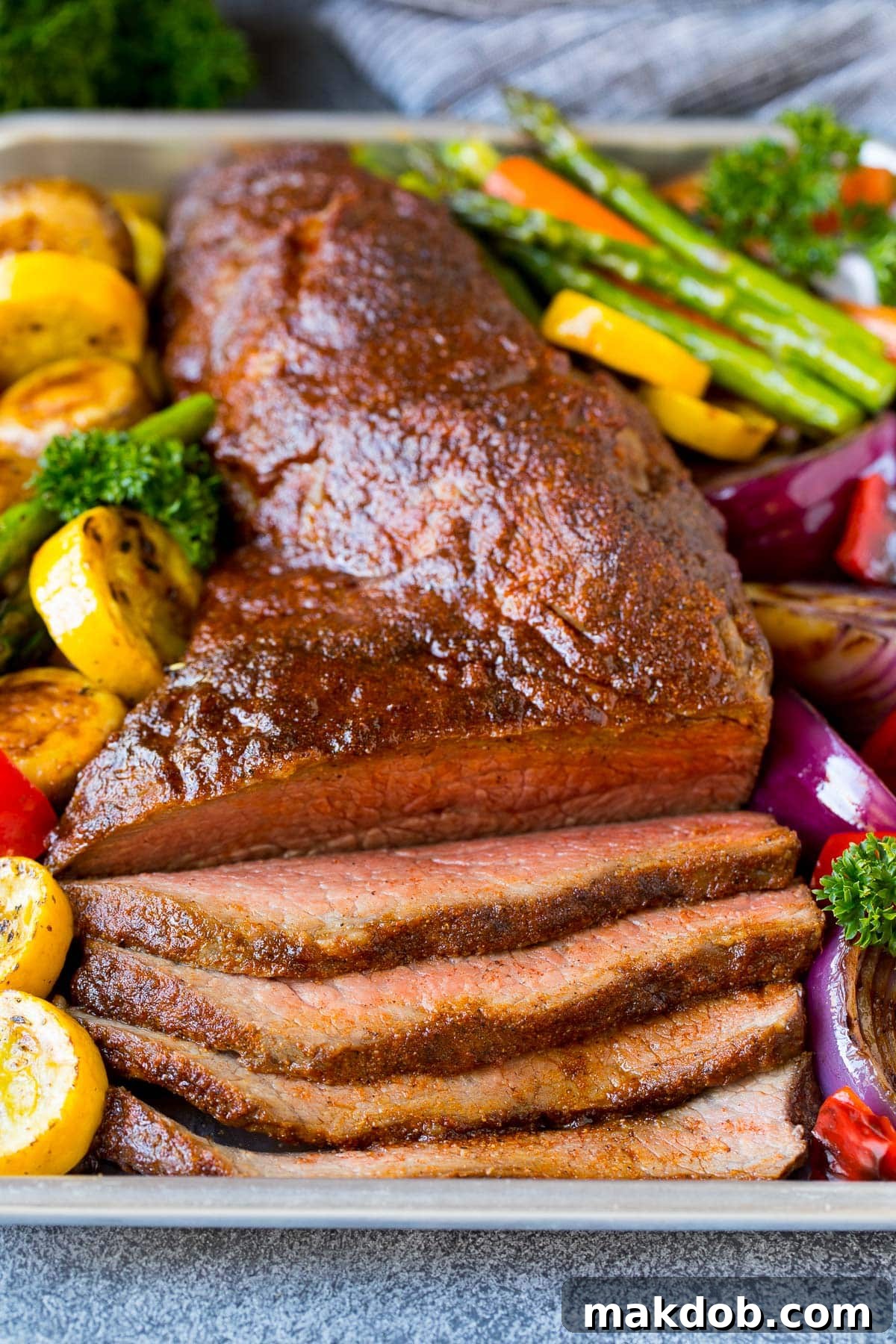 Smoky Tri Tip Perfection 2 A platter of beautifully sliced smoked tri tip served with fresh vegetables.