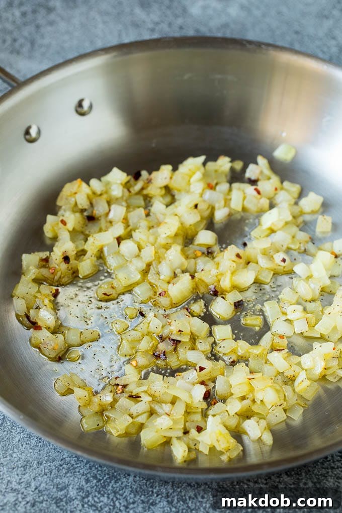 Finely diced onions sautéing in a hot skillet with olive oil, becoming translucent and fragrant.
