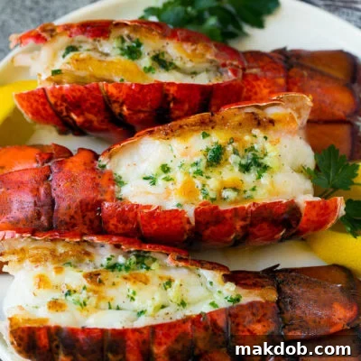 Grilled lobster tail topped with garlic butter and garnished with lemon and parsley.