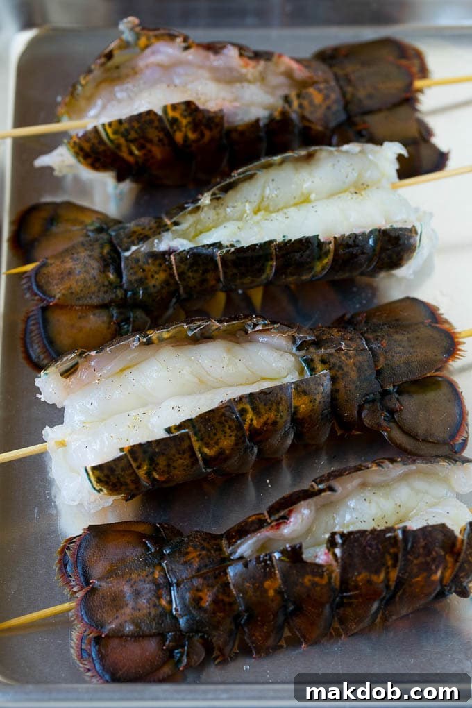 Raw lobster tails, perfectly split open and flattened with skewers inserted to prevent curling during grilling.