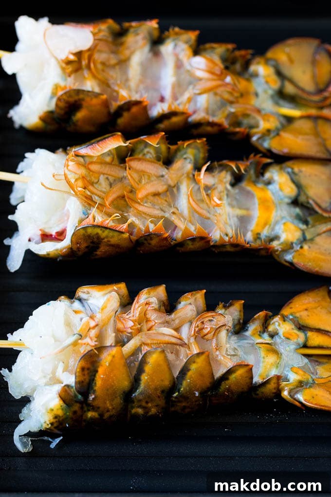 Lobster tails cooking on a grill pan, flesh side down, displaying perfect grill marks.